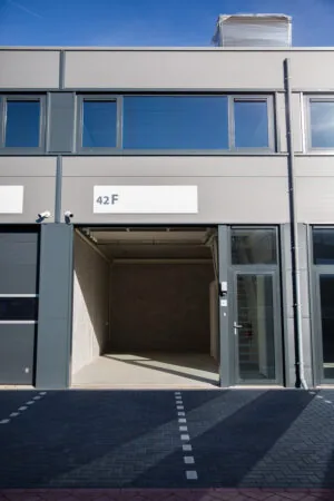 Bedrijfsunit 42F aan de Laan van s-Gravenmade met open roldeur en glazen entree.